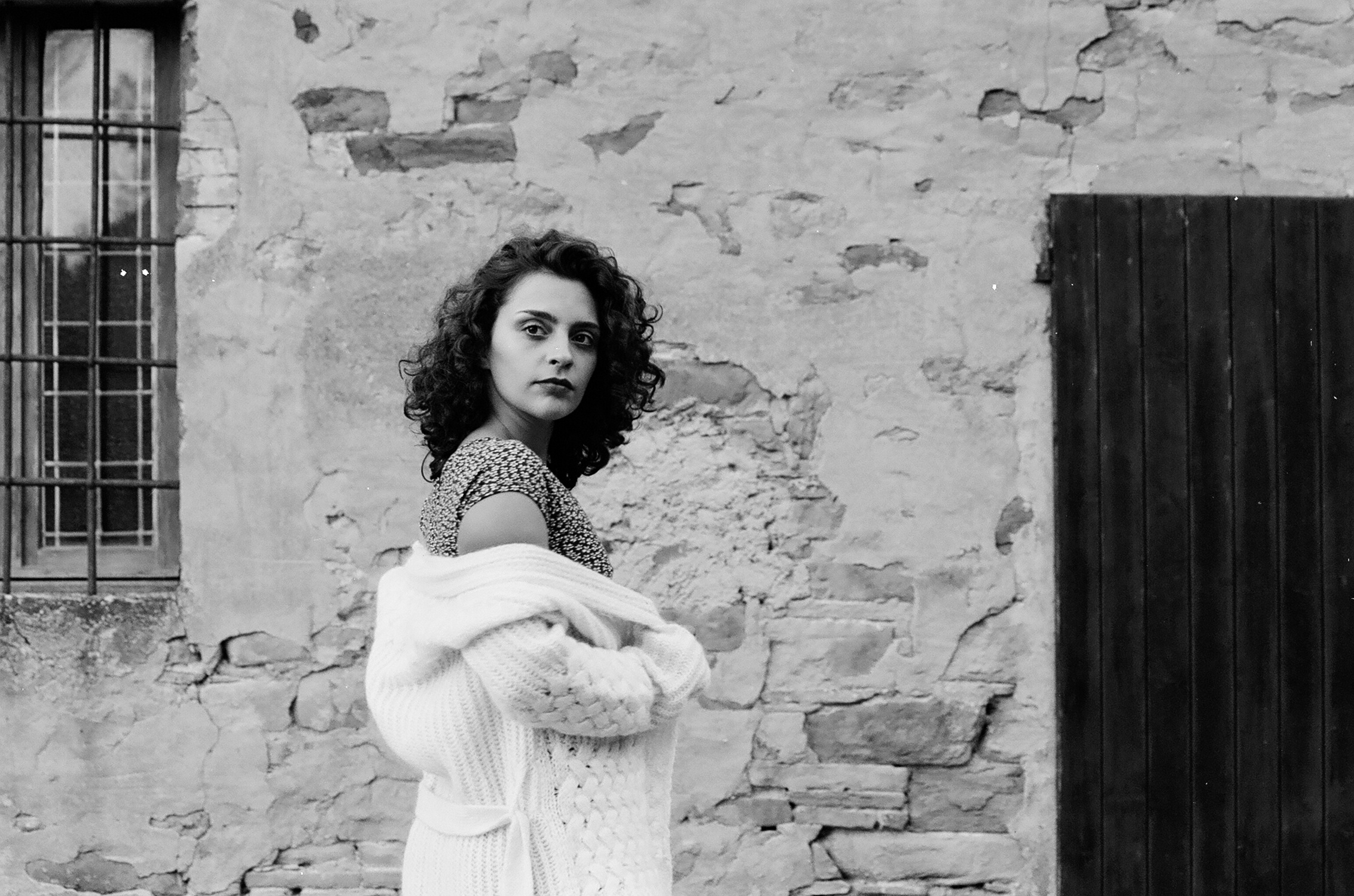 Ritratto in bianco e nero di ragazza con vestito a fiori e cardigan, fotografia analogica e vintage