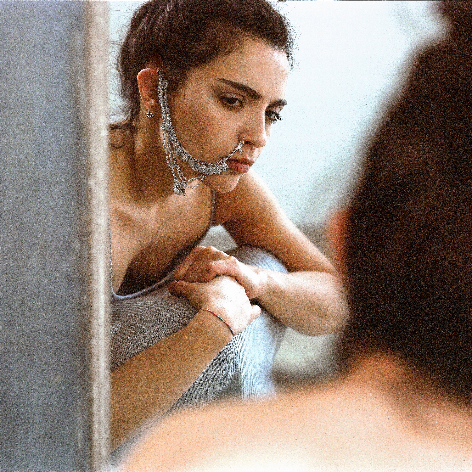 Ritratto di ragazza con piercing etnico davanti allo specchio, fotografia analogica medio formato